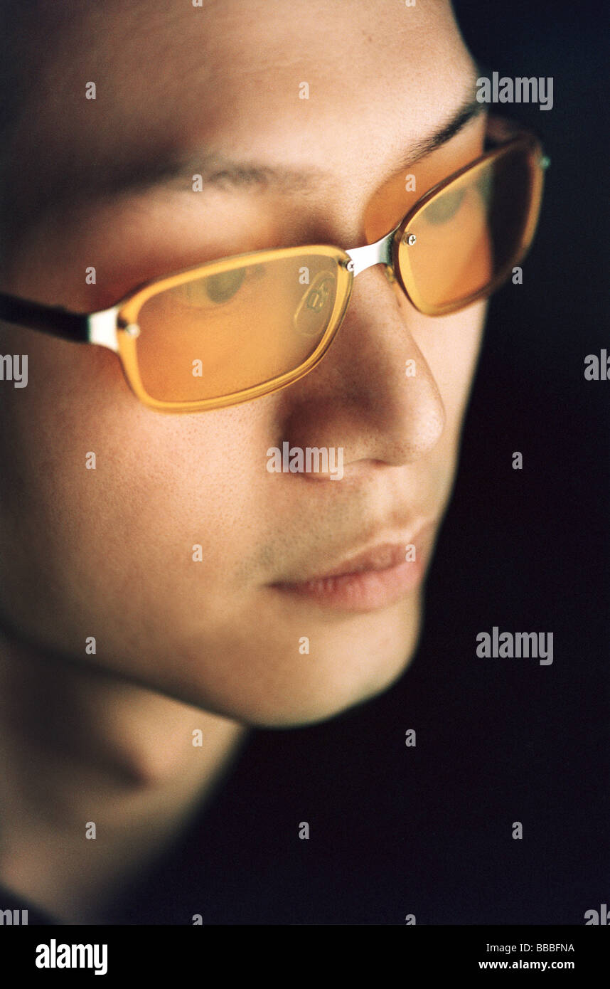 Uomo che indossa gli occhiali colorati, profilo laterale, sfondo nero Foto Stock
