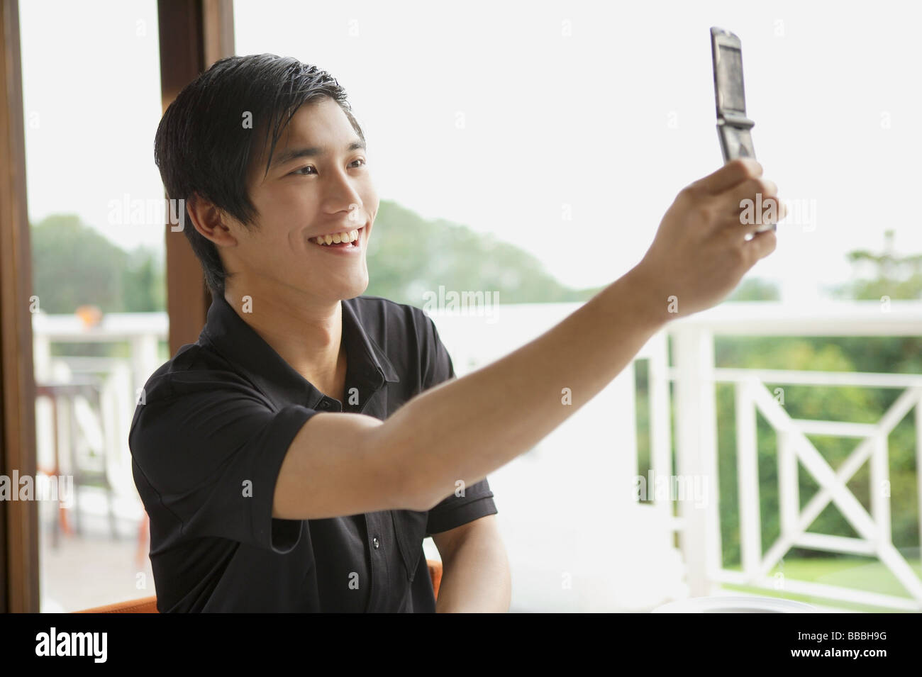 Uomo in cafe utilizzando il telefono cellulare per scattare una foto di se stesso Foto Stock