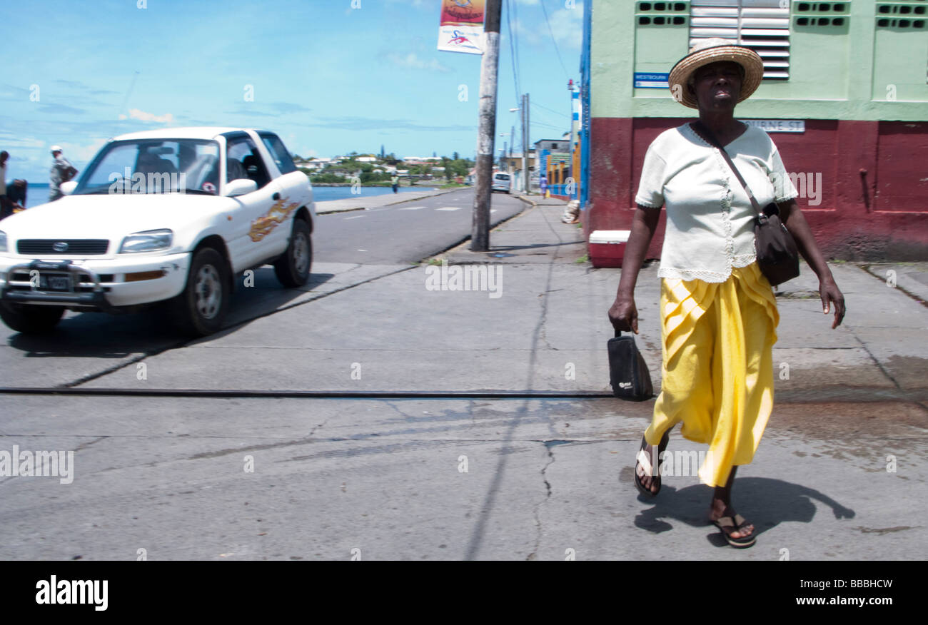 La donna residente locale nel cappello di paglia a camminare sulla strada della baia di capitale Basseterre St Kitts Foto Stock