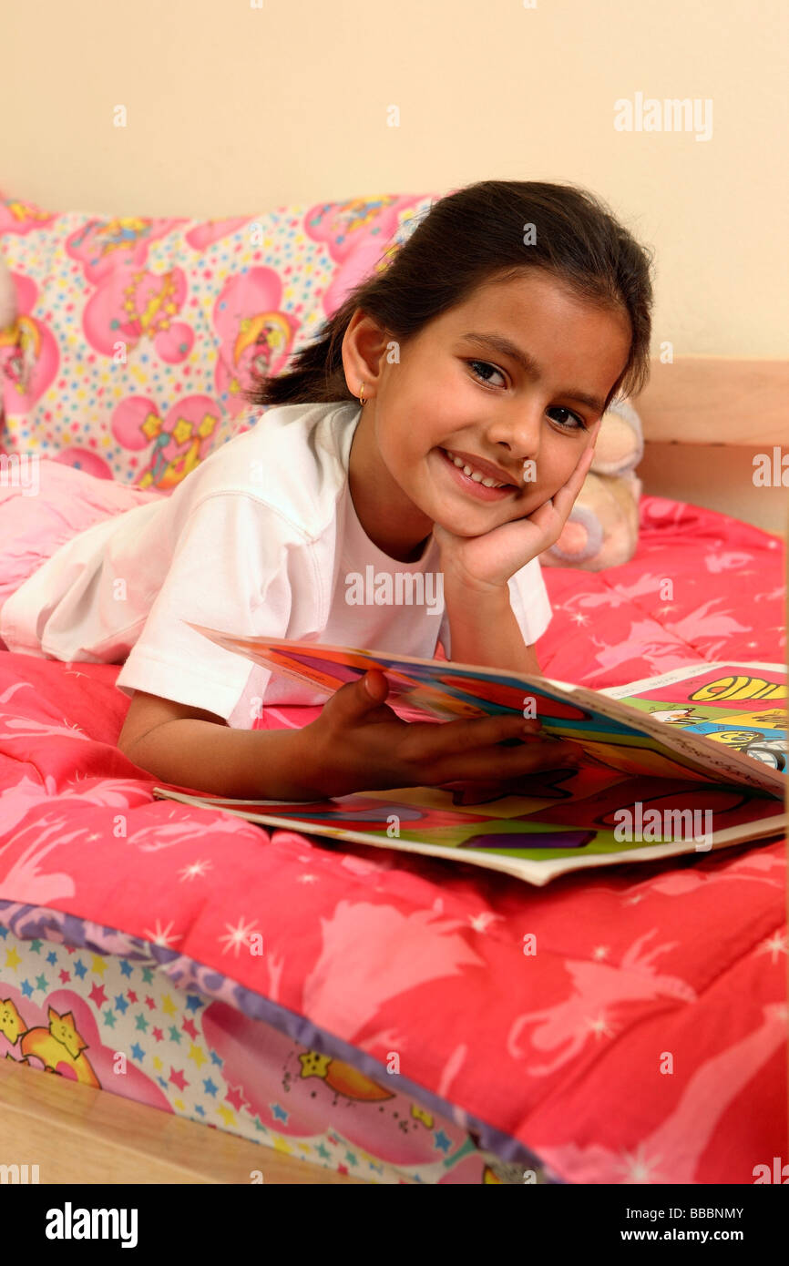 Lettura della ragazza prenota nel letto Foto Stock