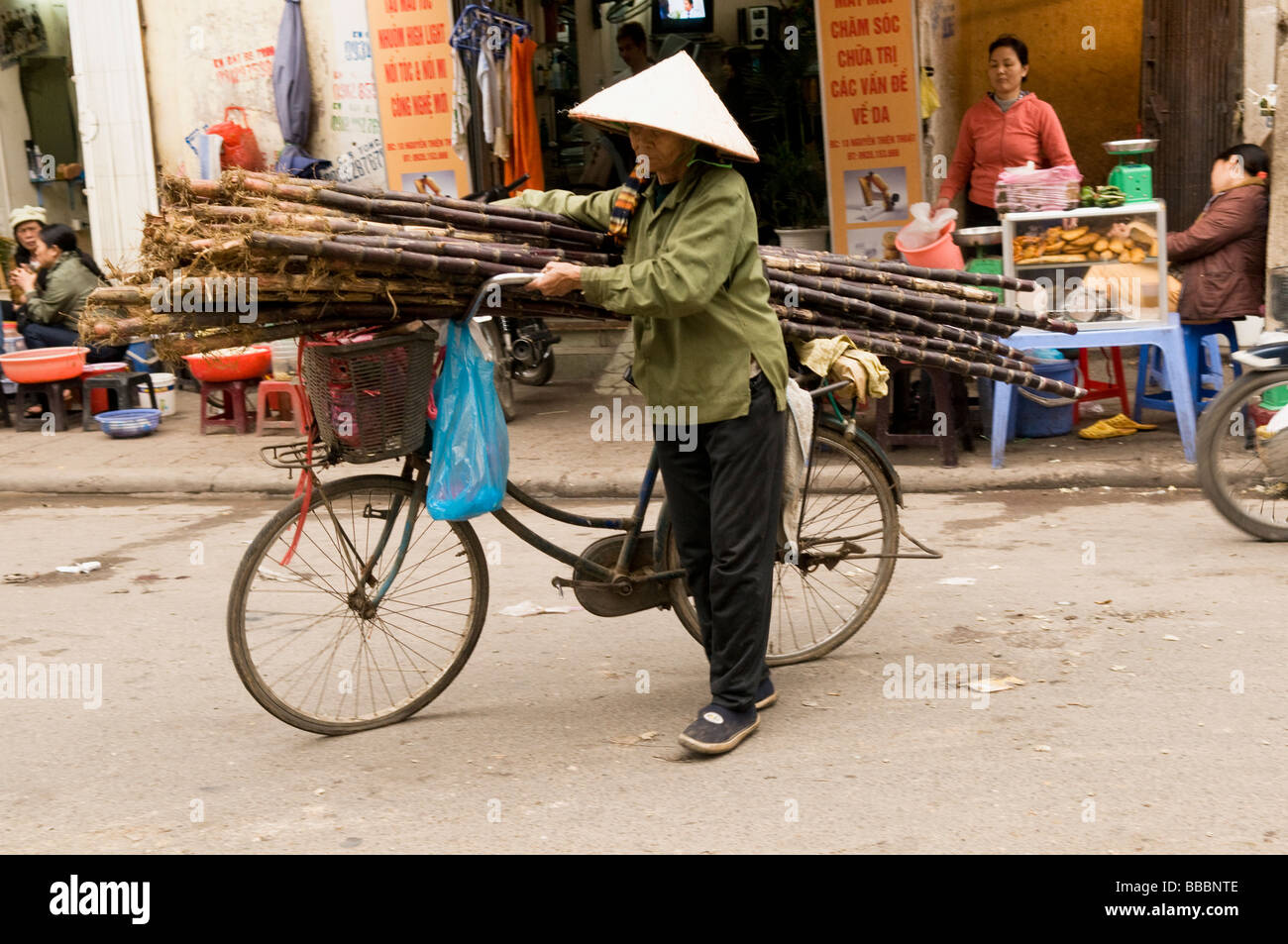 Old Lady con la canna da zucchero per la sua bicicletta per vendere, il vecchio quartiere di Hanoi, Vitenam. Foto Stock
