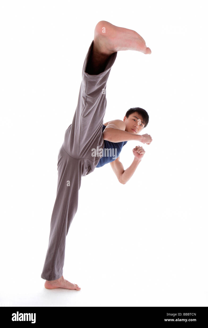 Giovane praticante di arti marziali, calci Foto Stock