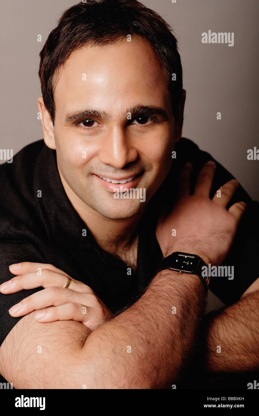 Uomo con le braccia incrociate, sorridente in telecamera Foto Stock