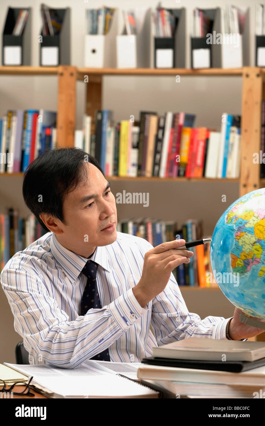 Un uomo che lavora con un globo sulla scrivania Foto Stock