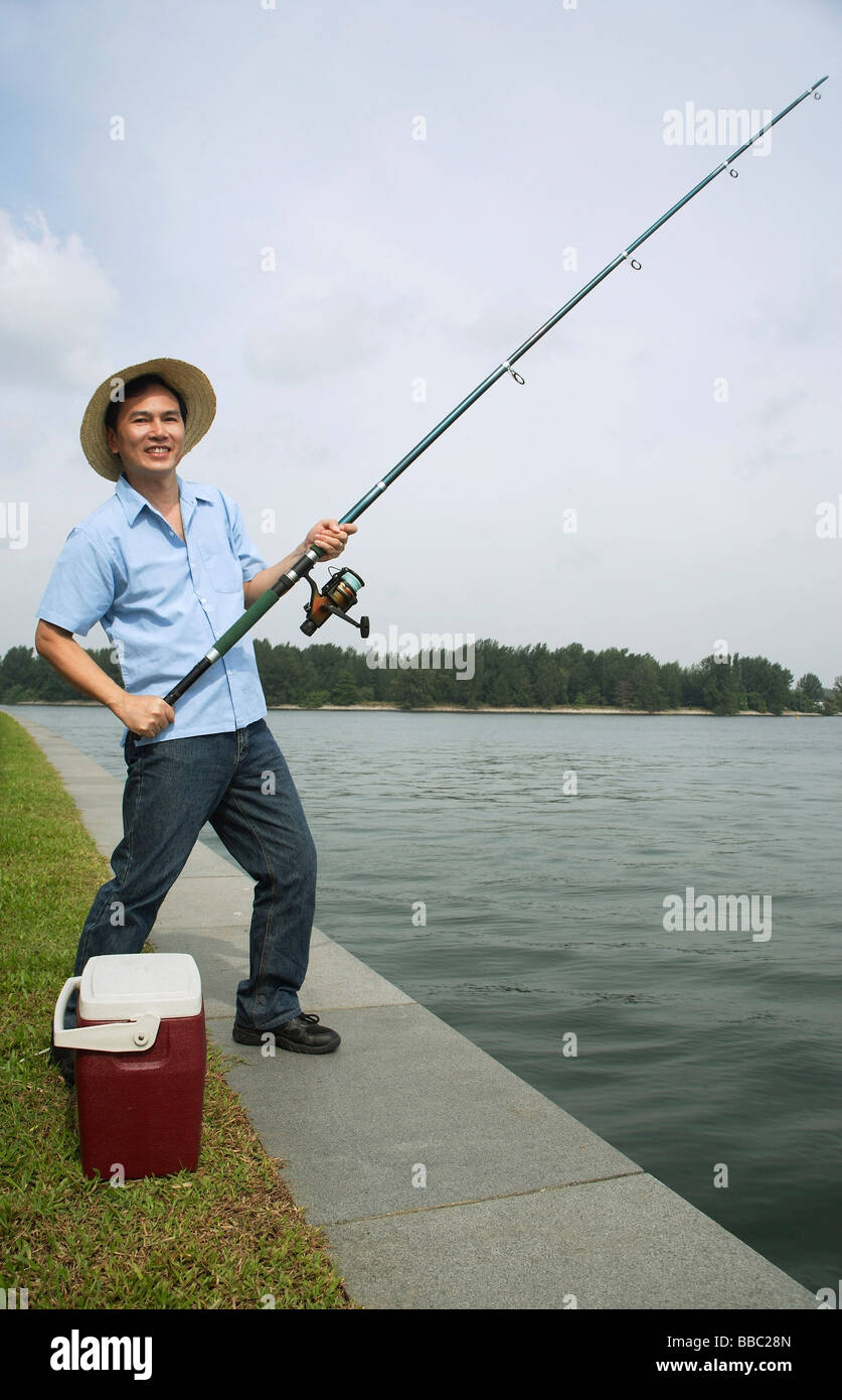L'uomo la pesca con la canna da pesca, guardando la telecamera, sorridente  Foto stock - Alamy