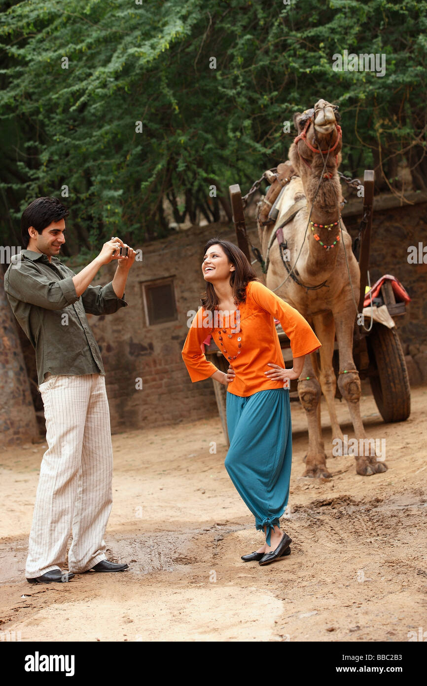 L'uomo prendendo foto della donna di fronte a cammello Foto Stock