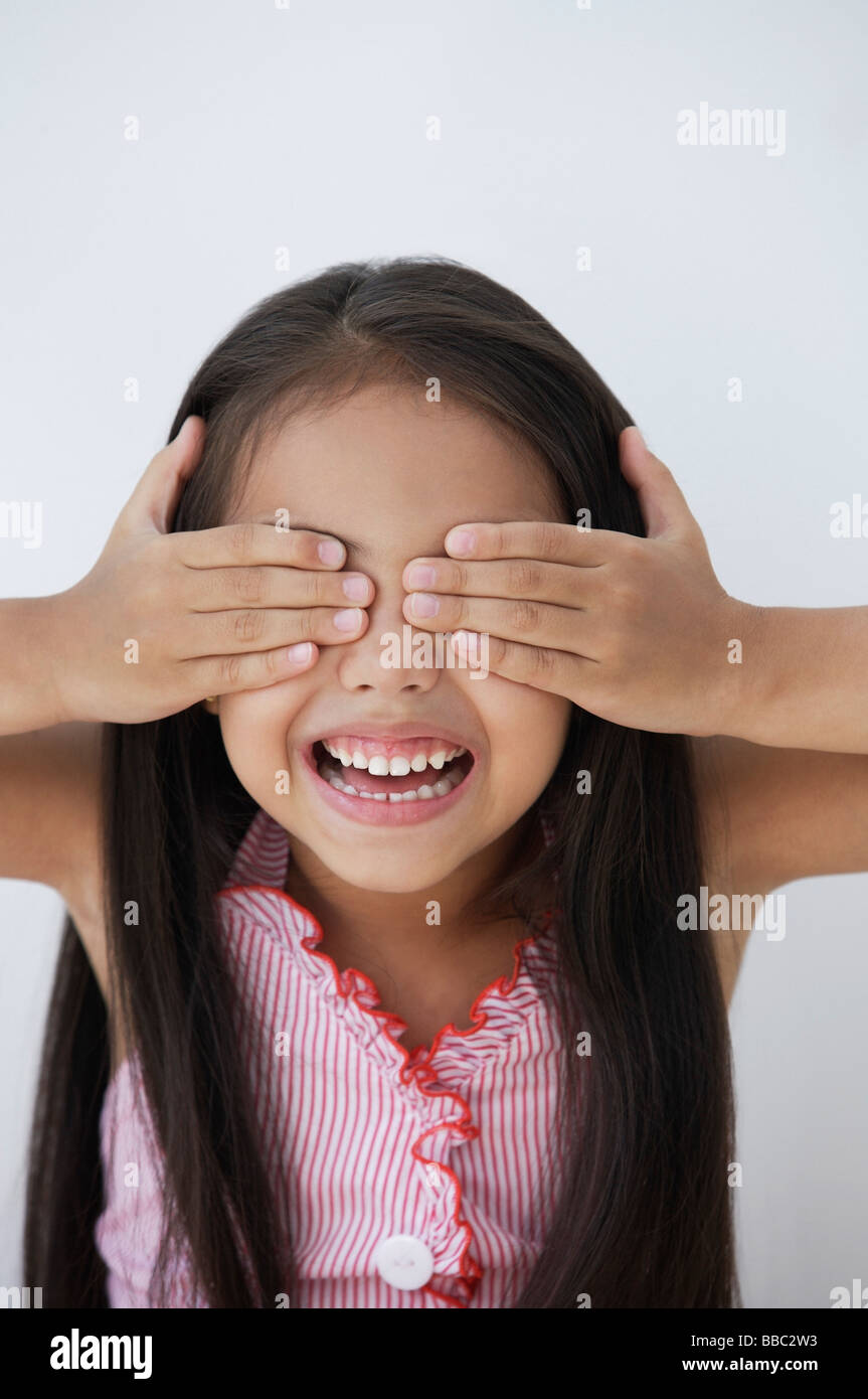 Una giovane ragazza copre gli occhi con le mani Foto Stock