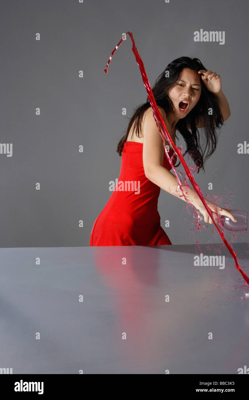 Frustrati giovane signora in rosso, schizzi di vino sul tavolo Foto Stock