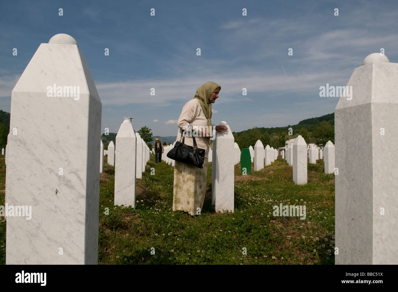 Una donna musulmana bosniaca cammina tra tombe dei suoi parenti, vittime del genocidio Srebrenica, nel cimitero di Potocari, vicino a Srebrenica, in Bosnia Foto Stock