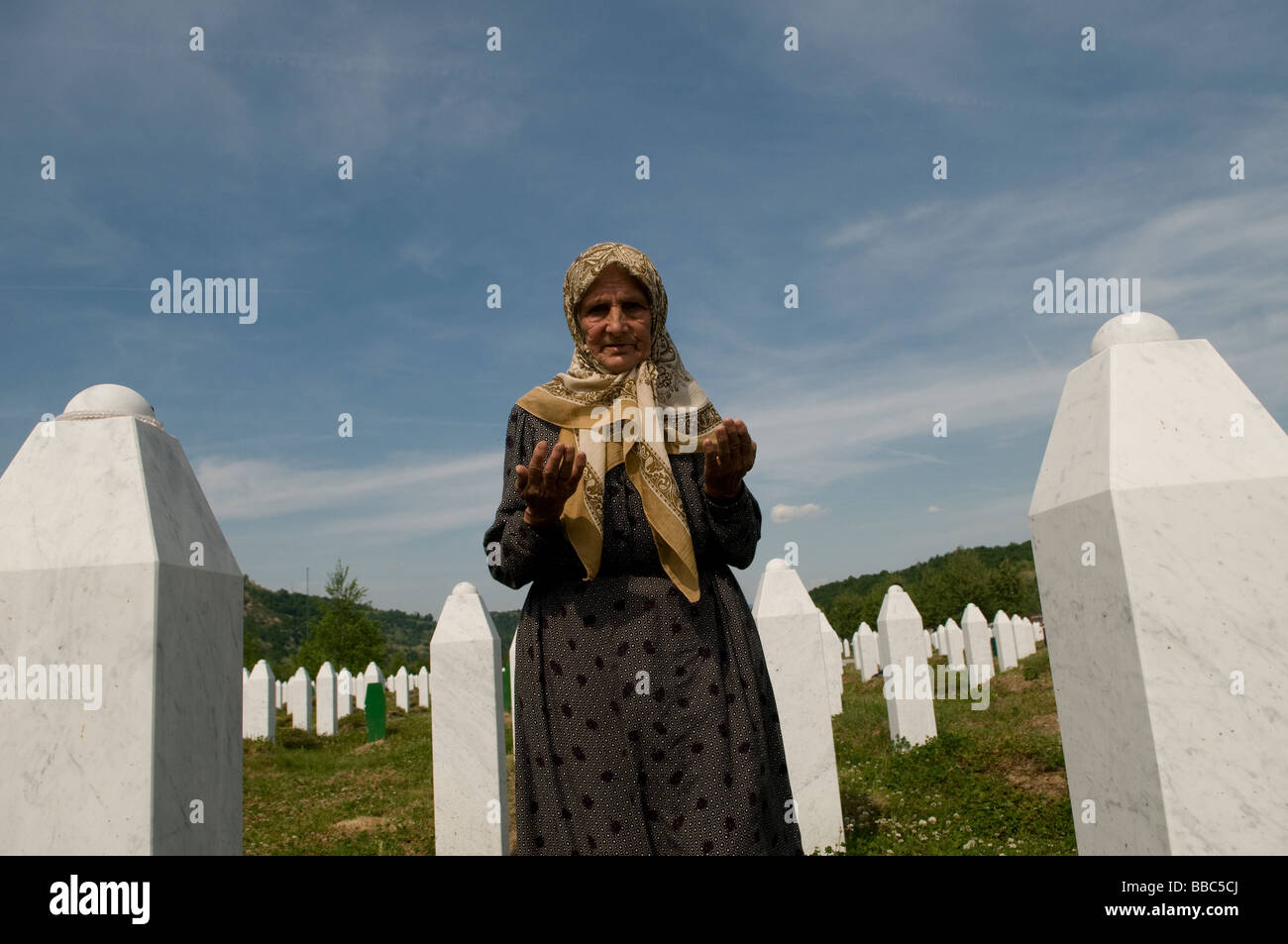 Una donna musulmana bosniaca prega tra le tombe dei suoi parenti, vittime del genocidio di Srebrenica, nel cimitero di Potocari vicino a Srebrenica, in Bosnia Foto Stock
