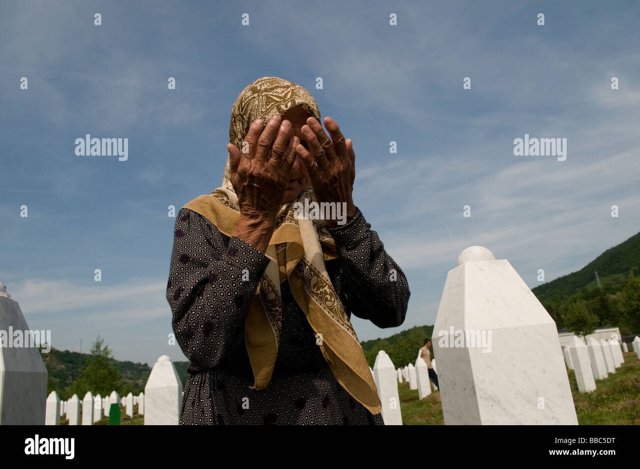 Una donna musulmana bosniaca piange tra tombe dei suoi parenti, vittime del genocidio Srebrenica, nel cimitero di Potocari, vicino a Srebrenica, in Bosnia Foto Stock