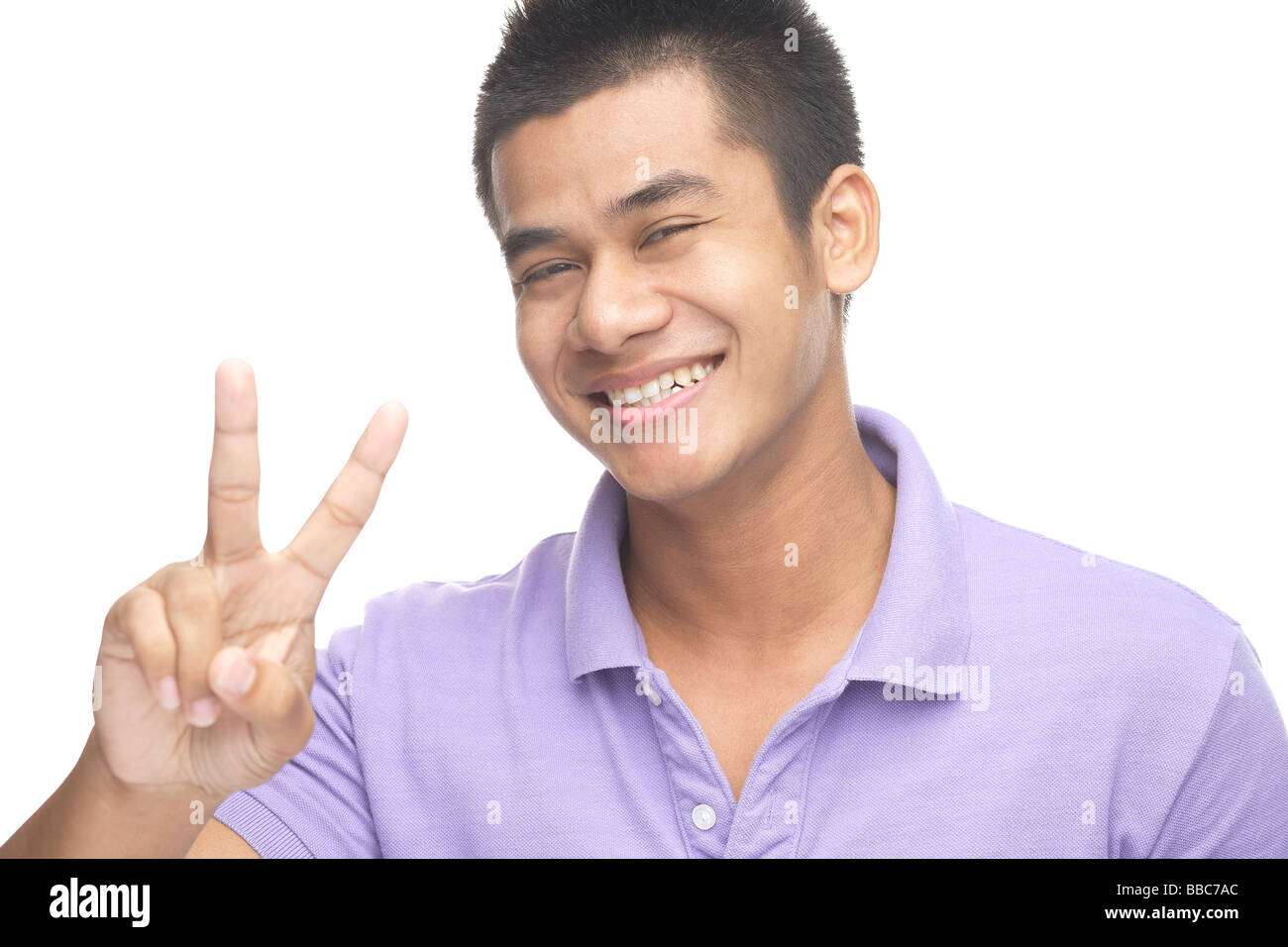 Uomo sorridente in telecamera, rendendo la pace segno a mano Foto Stock