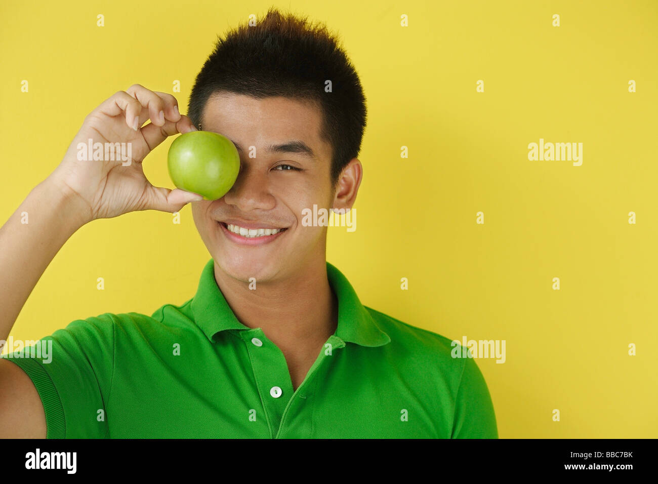 Uomo con mela verde sopra gli occhi, sorridente in telecamera Foto Stock