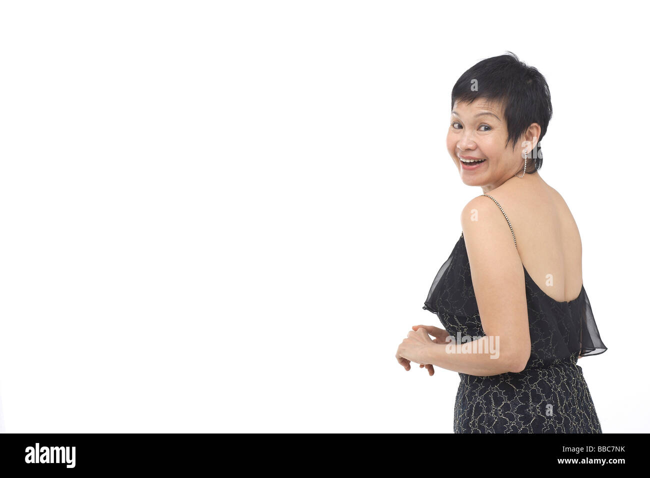 Donna matura in abito nero, guardando sopra la spalla Foto Stock