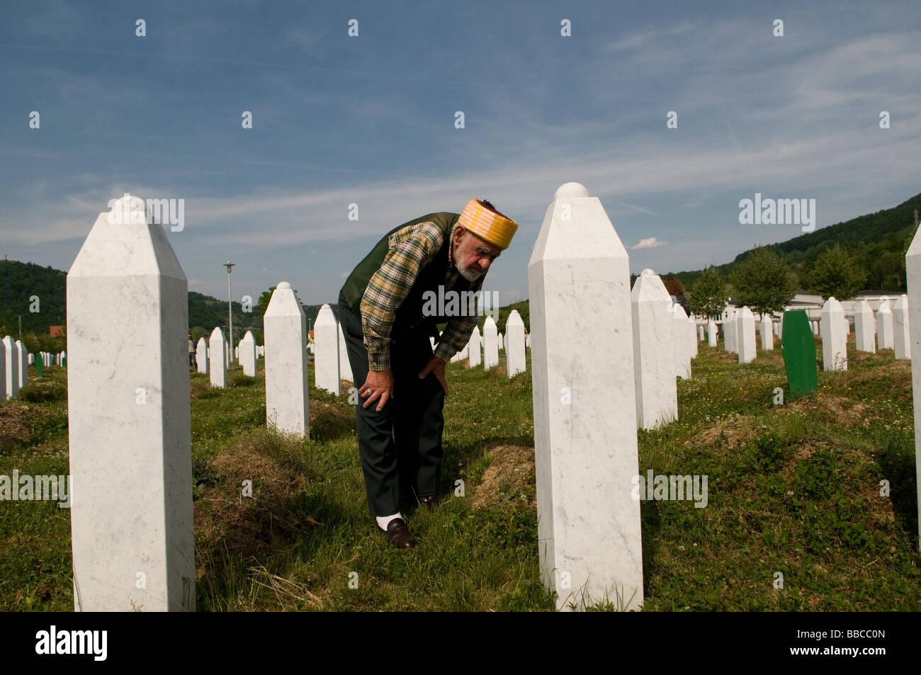 Un musulmano bosniaco si trova tra tombe dei suoi parenti, vittime del genocidio Srebrenica, nel cimitero di Potocari, vicino a Srebrenica, in Bosnia Foto Stock