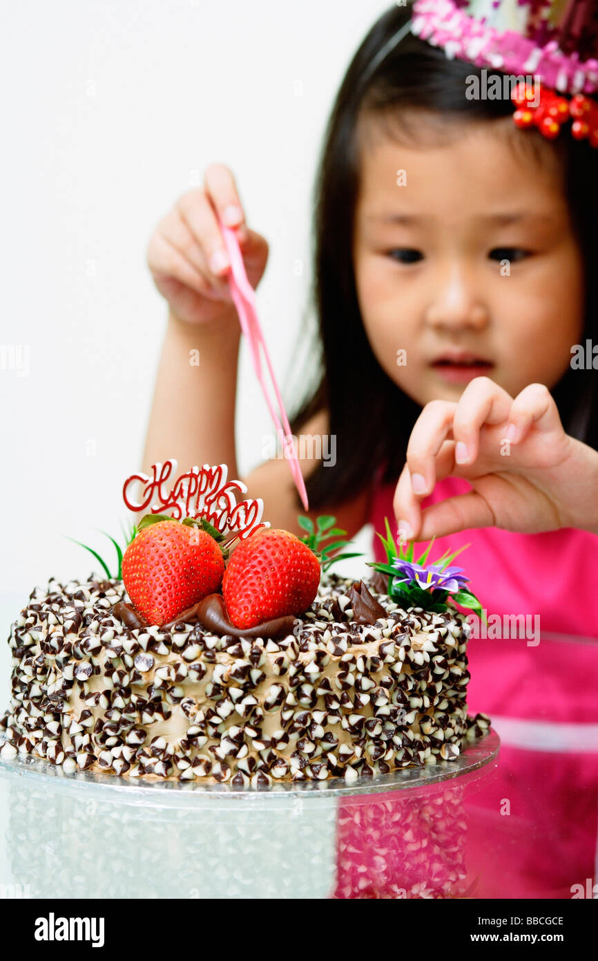 Ragazza di toccare la torta di compleanno Foto Stock