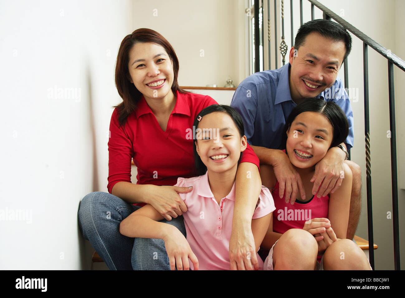 Famiglia con due ragazze, sorridente in telecamera Foto Stock
