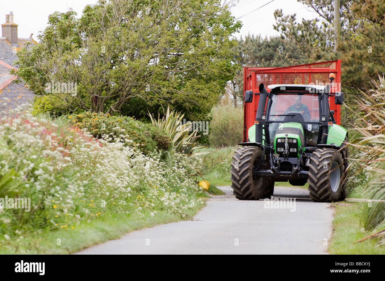 Grande trattore verde e rosso carrello su una piccola Cornish lane Foto Stock