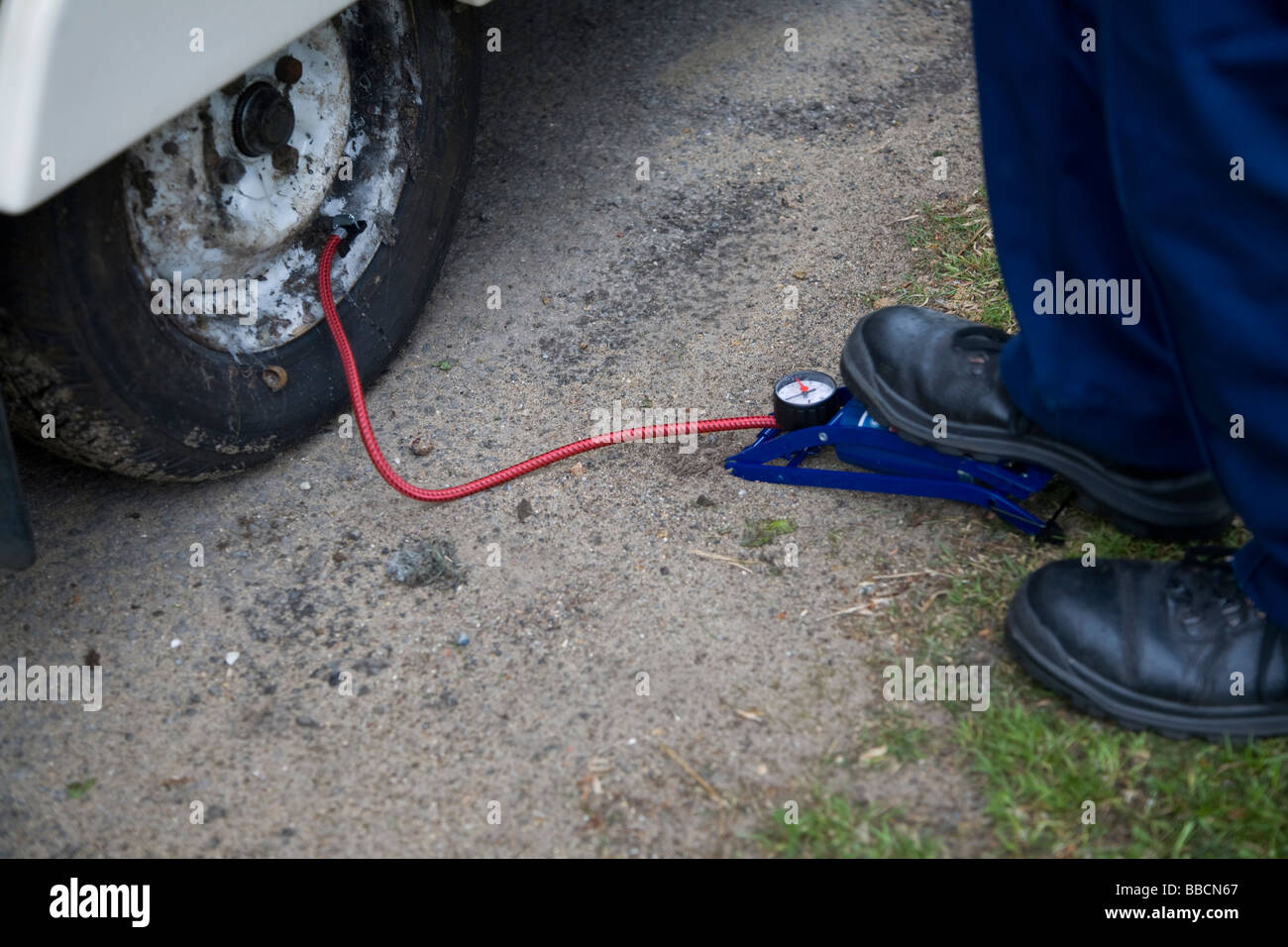 Il pompaggio di un pneumatico con una pompa a pedale Foto Stock