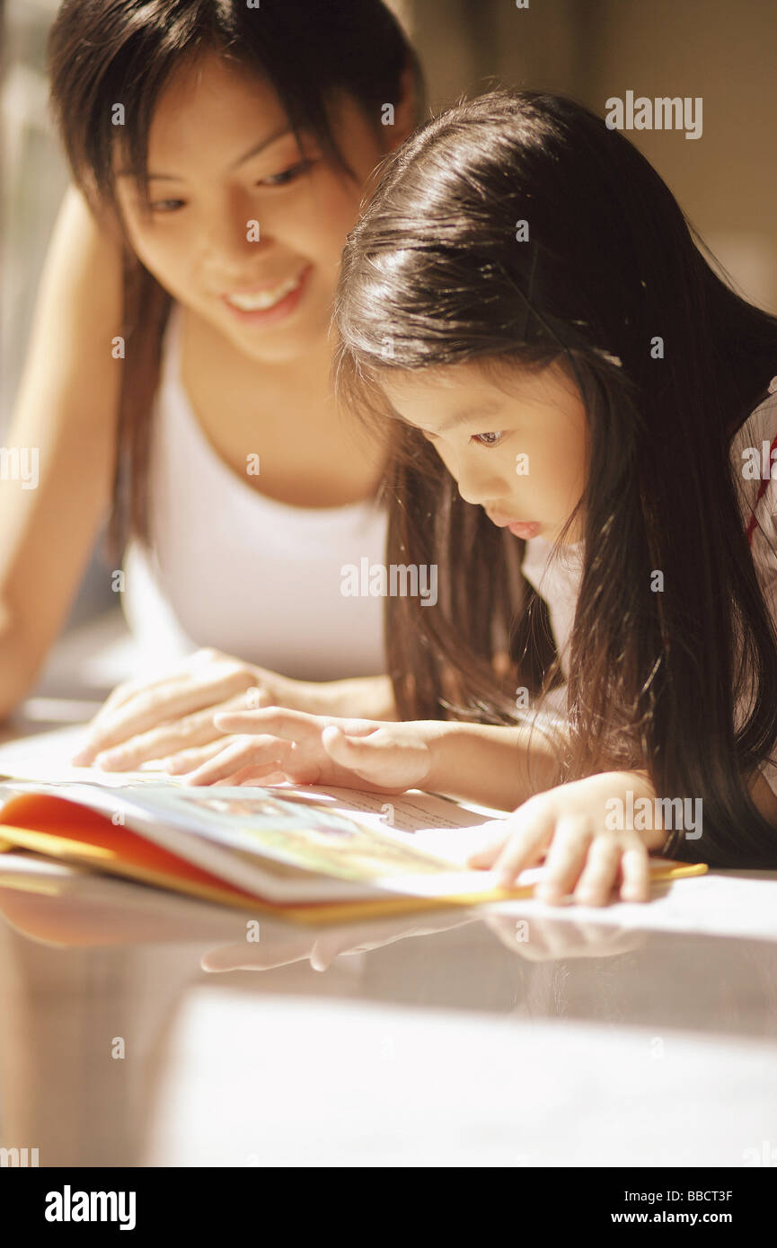 Madre e figlia, fianco a fianco, guardando il magazine Foto Stock