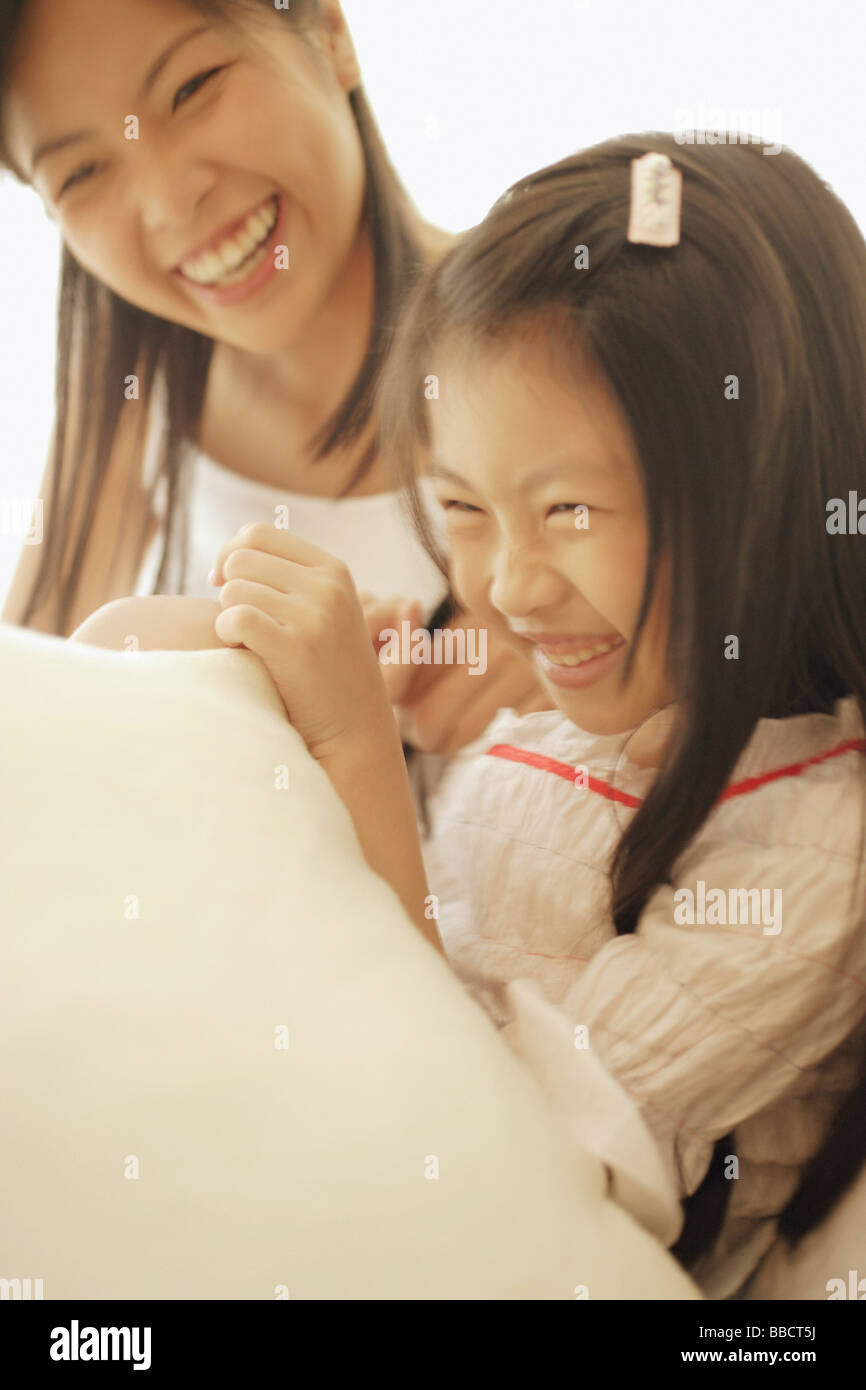 Madre e figlia seduti fianco a fianco, ridendo Foto Stock