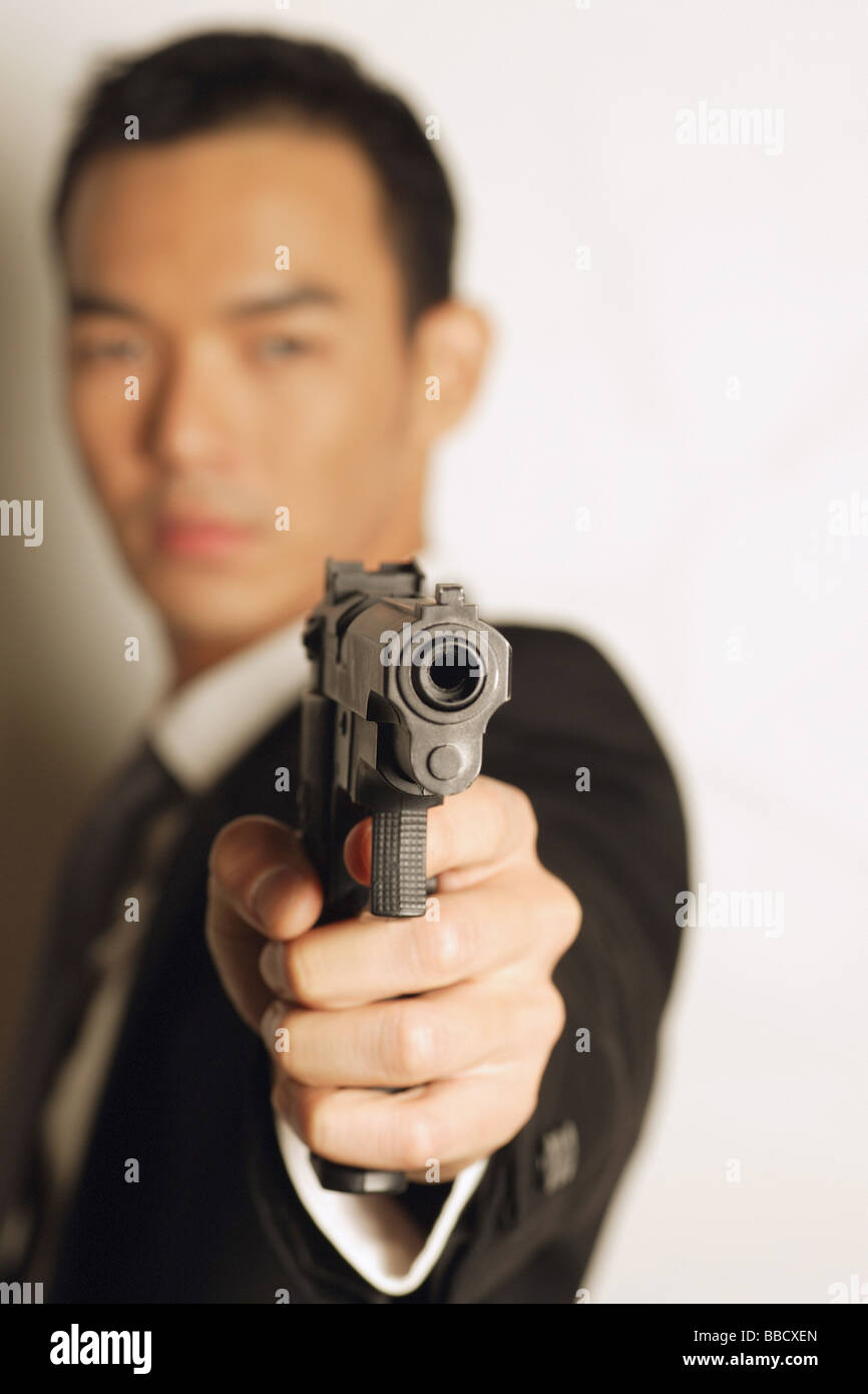 Uomo vestito con una tuta, pistola di puntamento Foto Stock