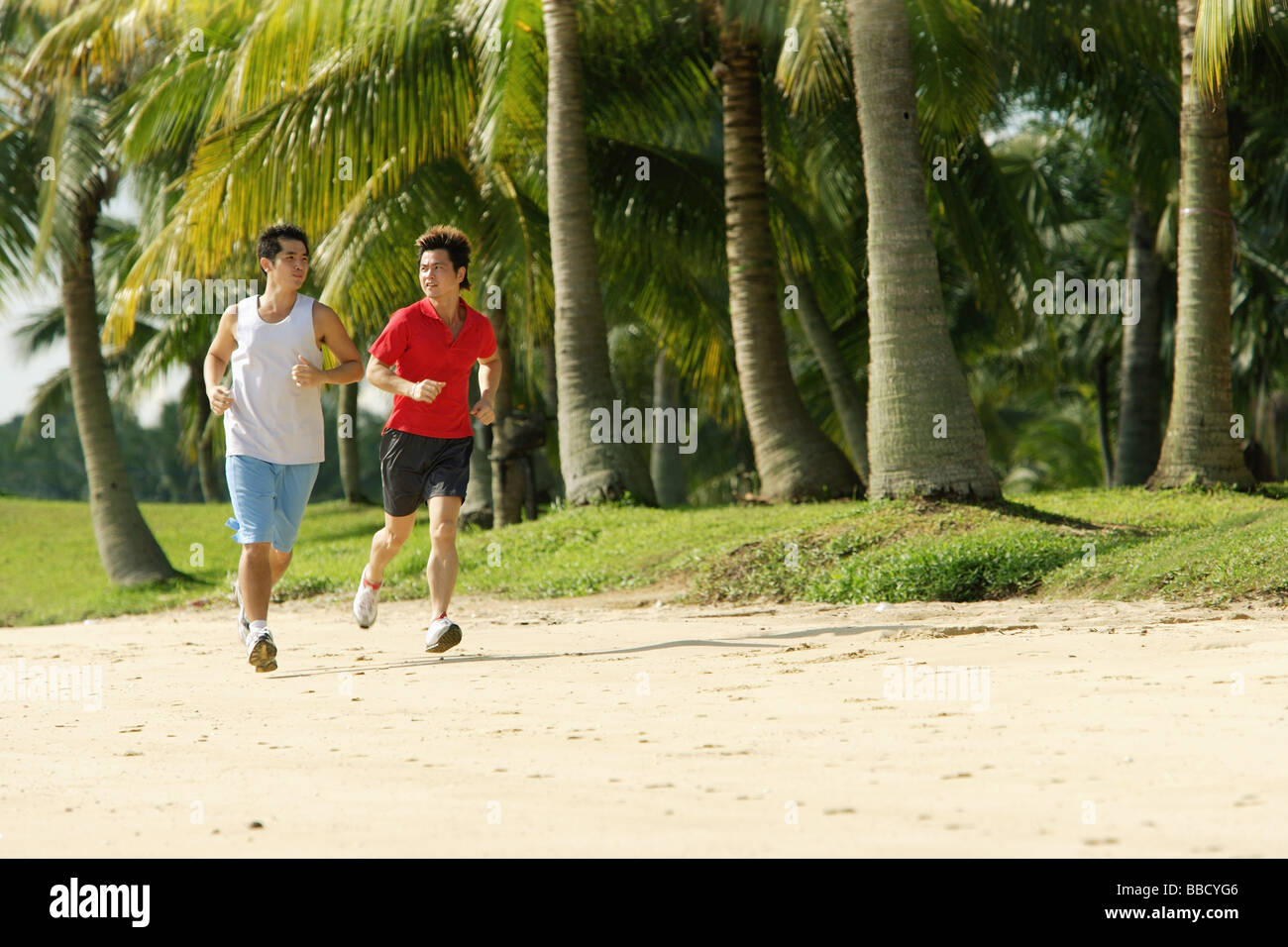 Gli uomini jogging lungo la spiaggia, fianco a fianco Foto Stock