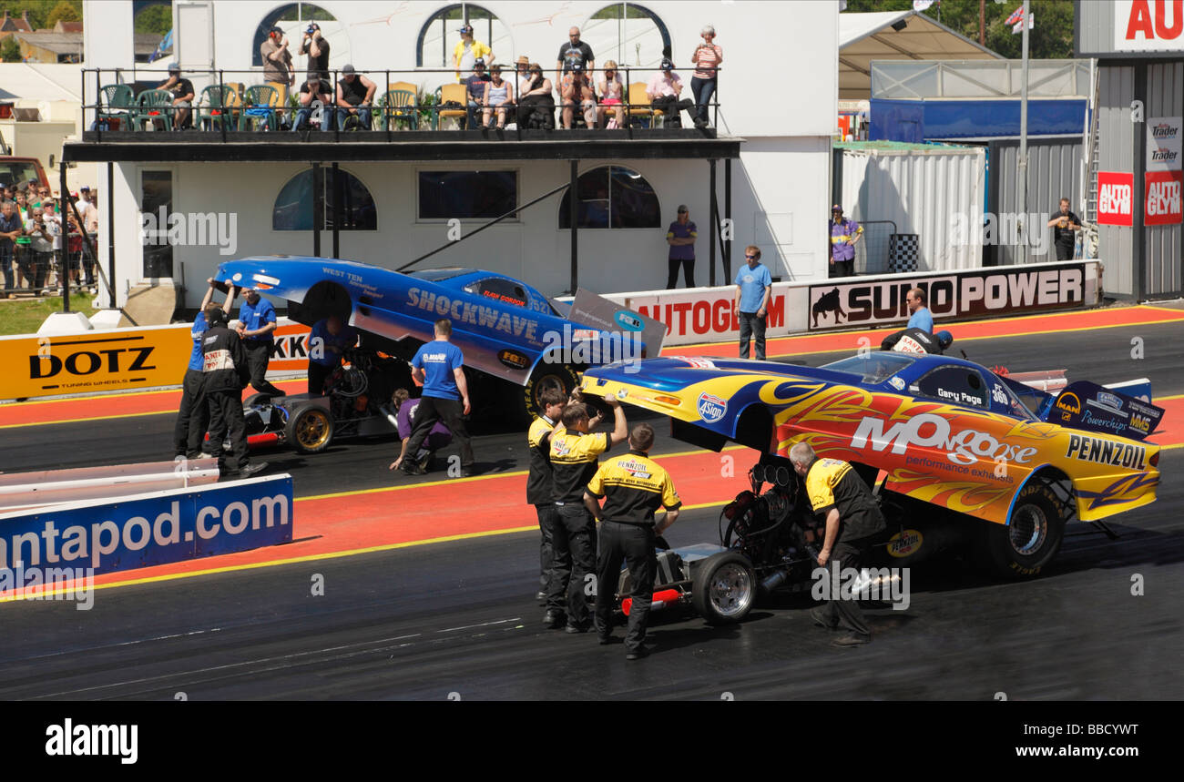Top Fuel Funny Cars dragsters essendo preparato per il racing. Santa Pod Raceway, Inghilterra, Regno Unito. Foto Stock