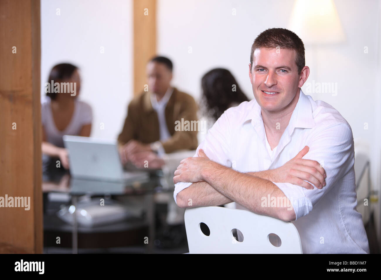 Ritratto di uomo caucasico in primo piano con co lavoratori in background Foto Stock