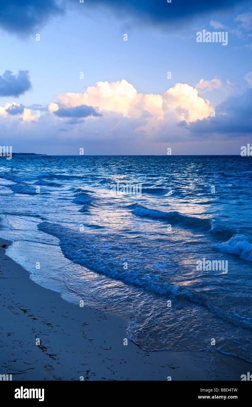 Le onde del mare sulla spiaggia al tramonto con nuvole soleggiato Foto Stock