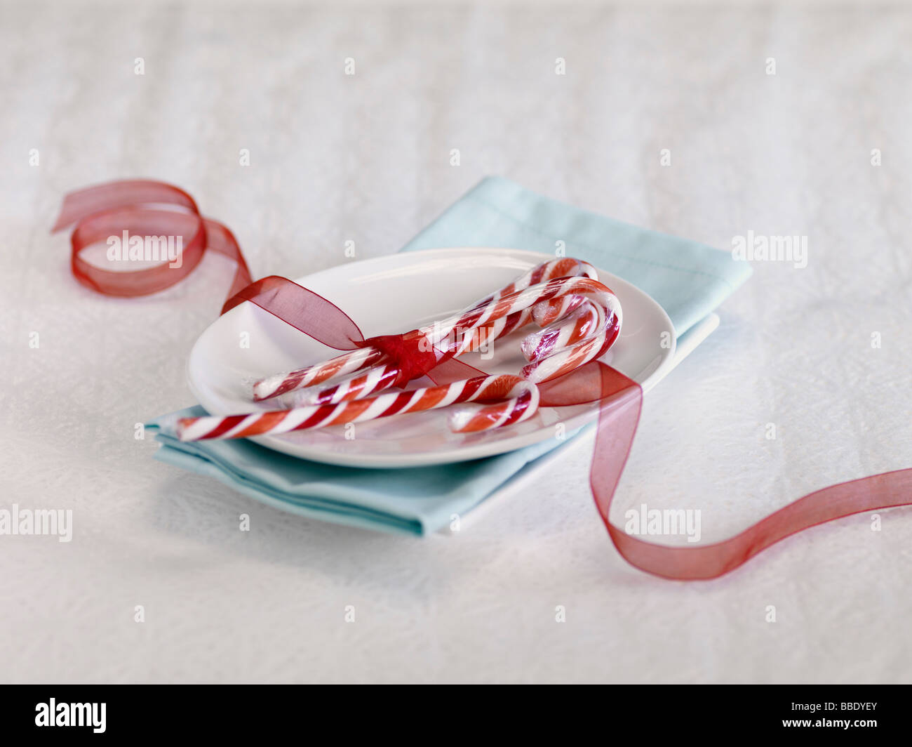 Candy Canes legate con un nastro rosso sulla piastra Foto Stock