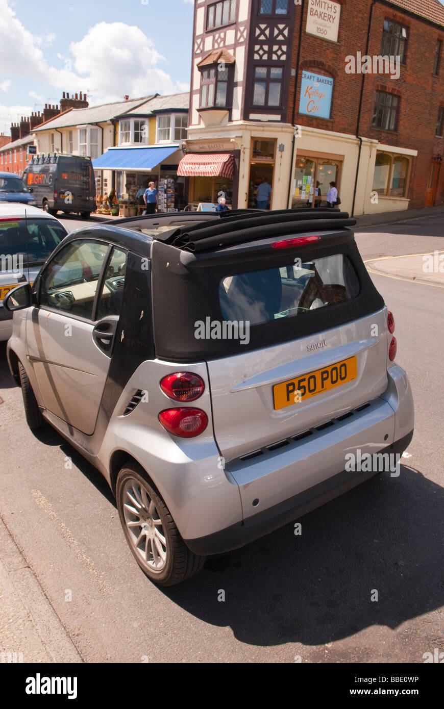 Una piccola economica eco friendly smart auto in una strada del regno unito che mostra la divertente numero personalizzato per la lettura della piastra poo Foto Stock
