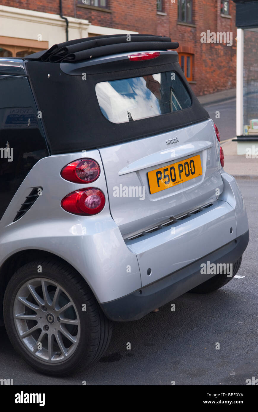 Una piccola economica eco friendly smart auto in una strada del regno unito che mostra la divertente numero personalizzato per la lettura della piastra poo Foto Stock