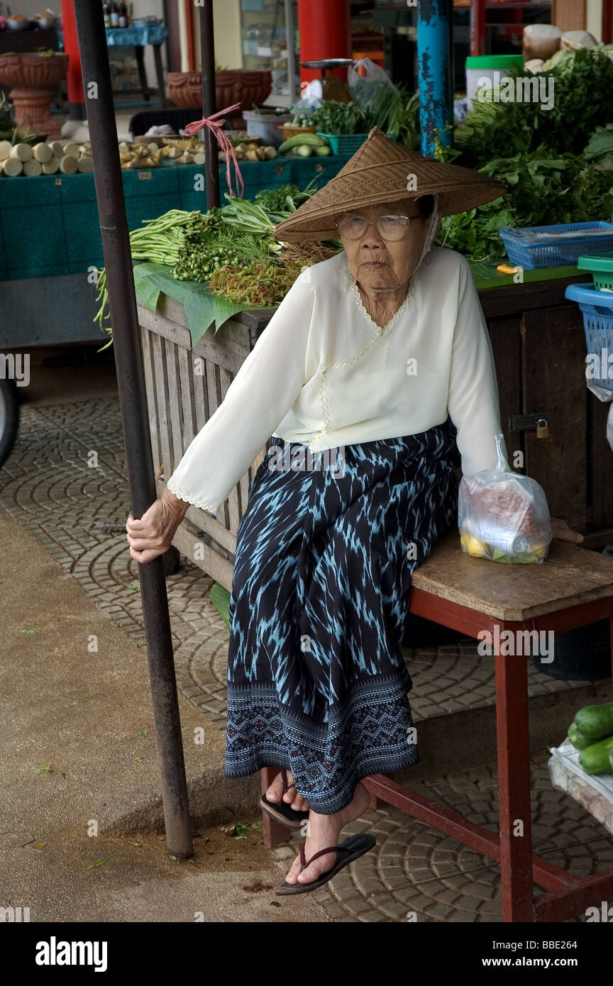 Donna anziana in attesa per il bus al di fuori del mercato di Mae Hong Son, Thailandia Foto Stock