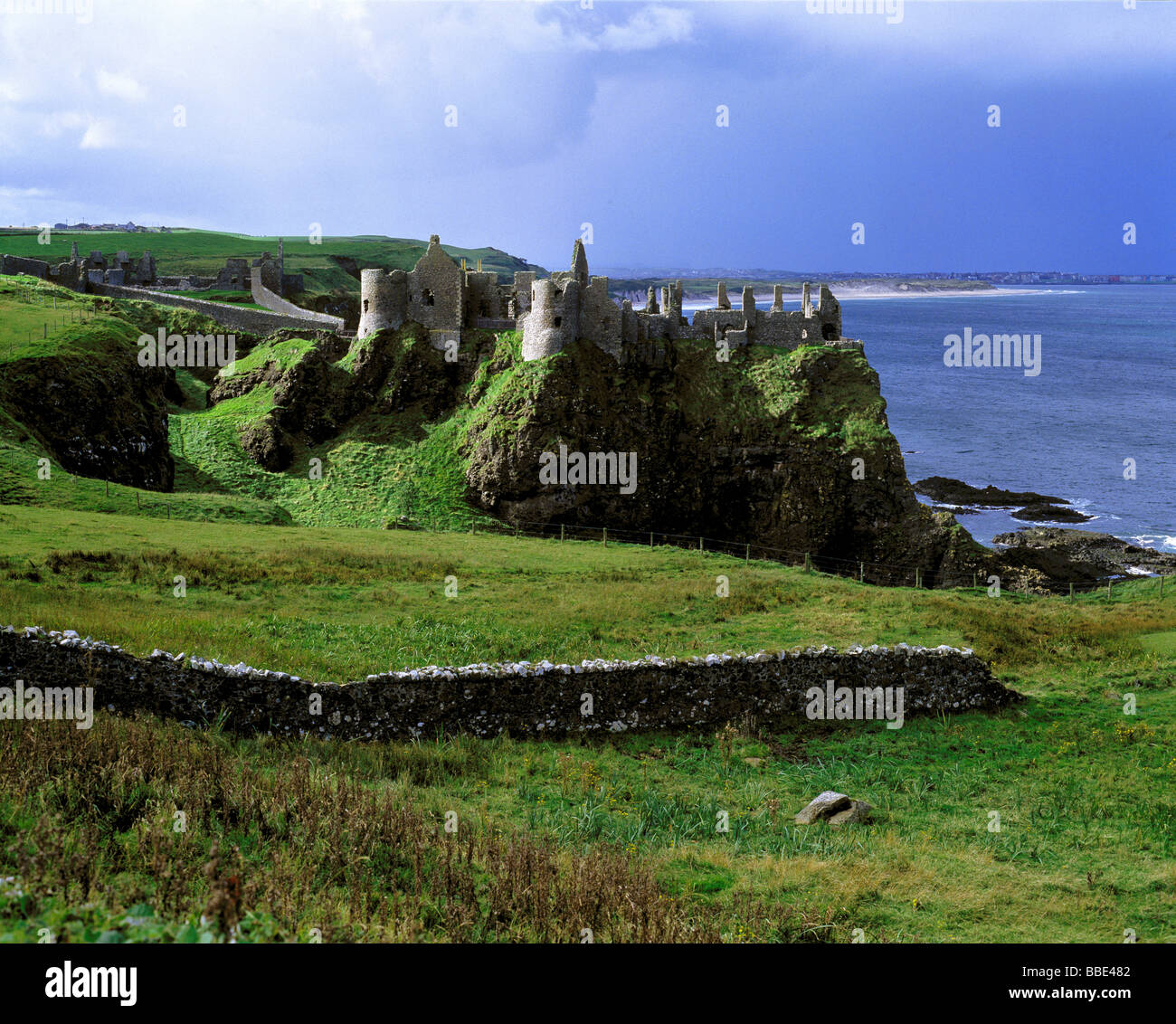 Dunluce Castle sorge dalle colline di smeraldo su Irlanda del Nord s costa di Antrim. Foto Stock