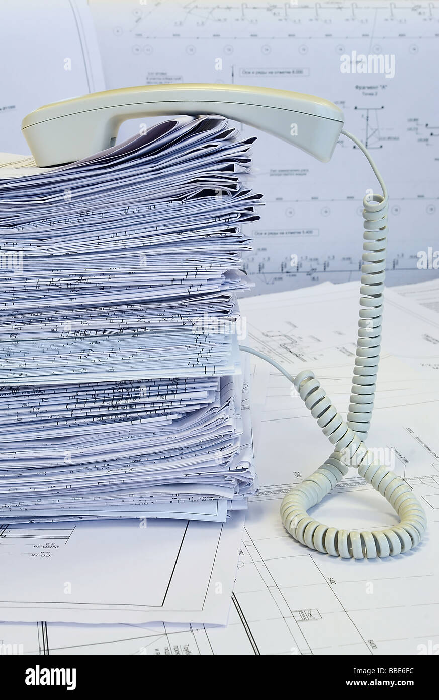 Ricevitore bianco sul mucchio dei disegni di progetto. White whatman sono lo sfondo. Telefono straordinario. Foto Stock