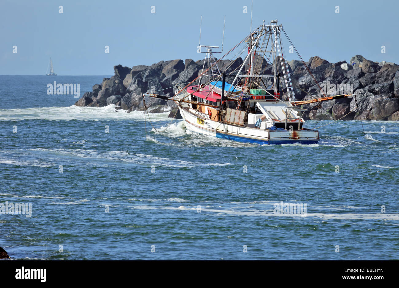 La pesca a strascico che passa attraverso una struttura di frangionde sulla sua strada verso l'oceano per una serata di pesca di gamberi Foto Stock