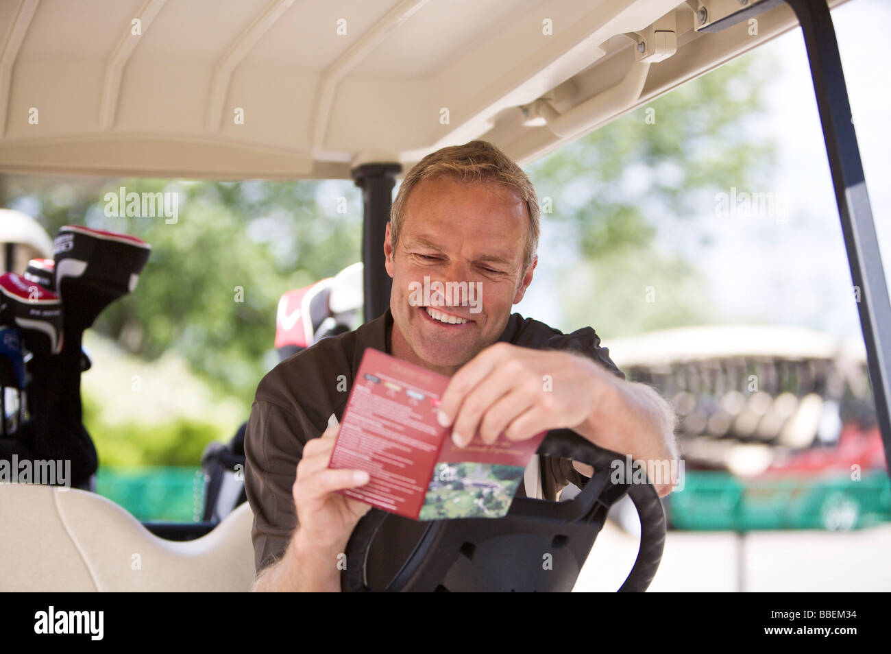 Uomo con score card in golf cart Foto Stock