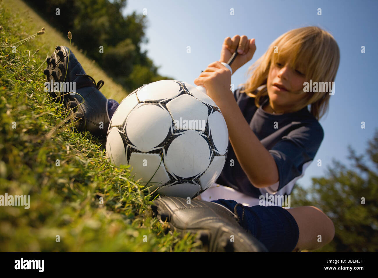 Giocatore di calcio pompare aria nel calcio Foto Stock