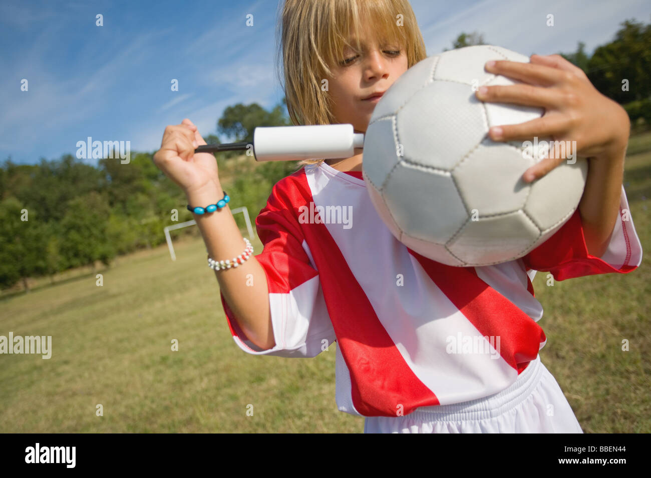 Giocatore di calcio calcio di contenimento e pompando aria Foto Stock