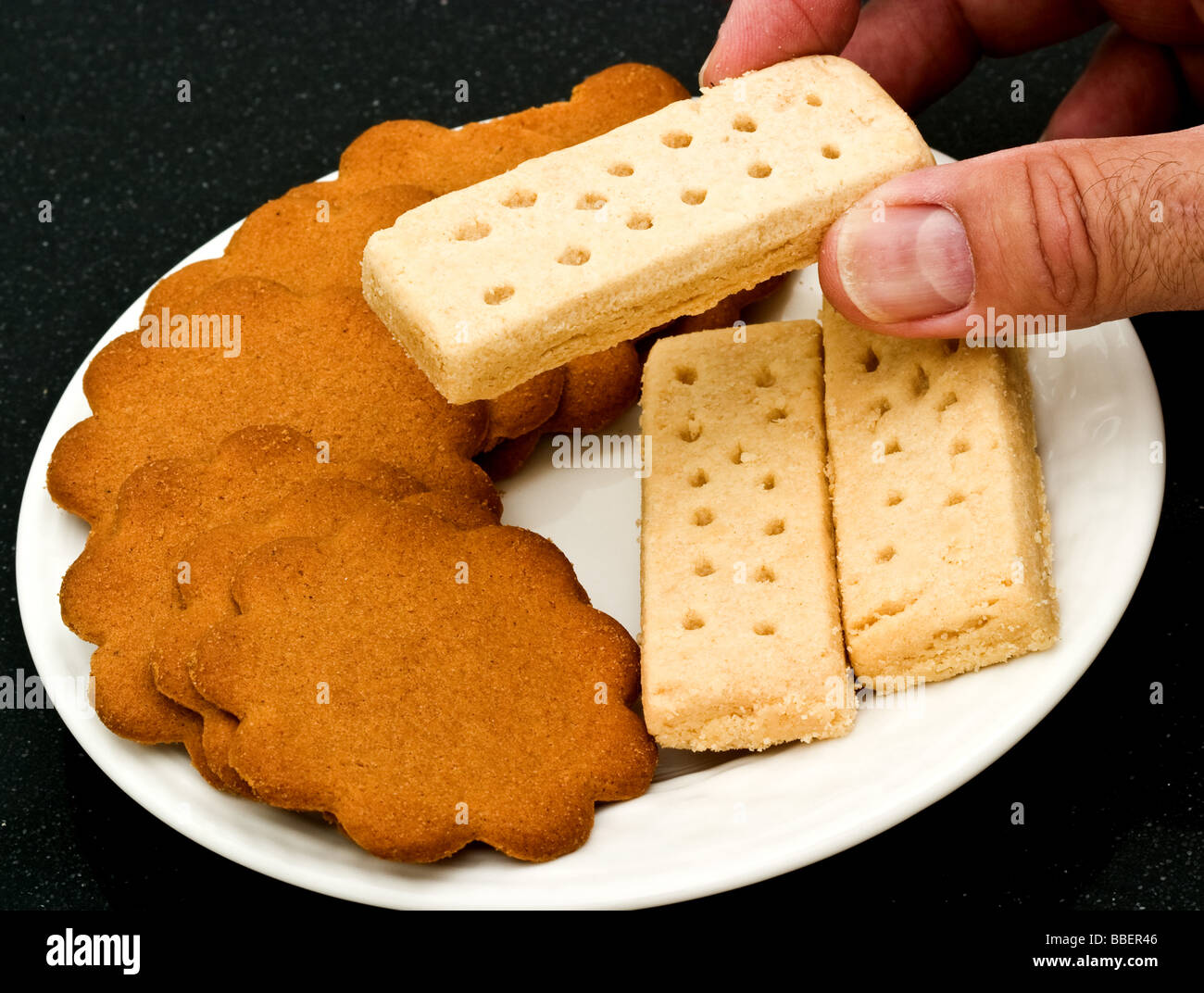 Tre biscotti frollini dita con lo zenzero scatta su una piastra bianca Foto Stock