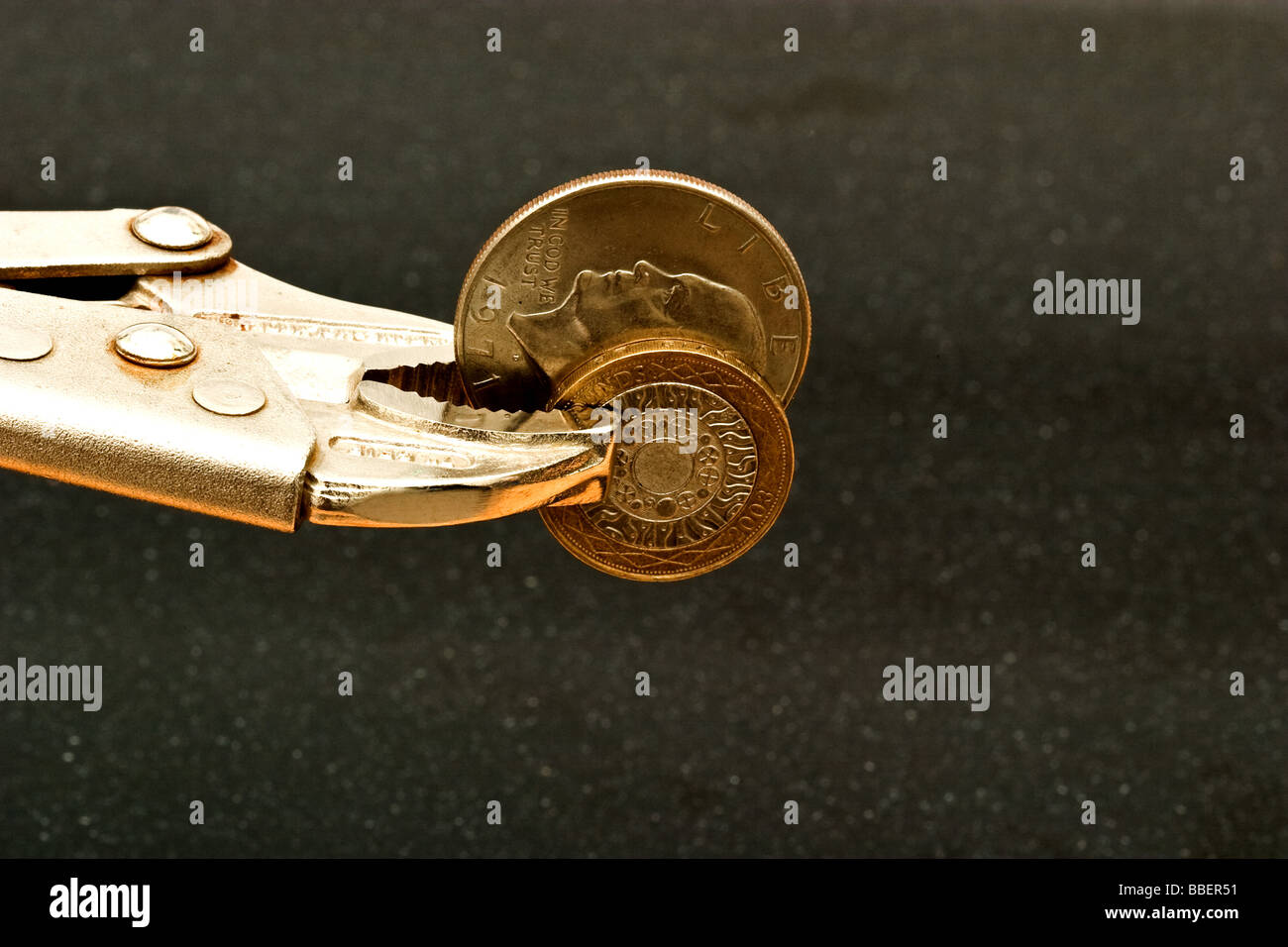 Metallo vise grip tenendo un American Silver Dollar coin e Inghilterra è un due libbre di rame e di argento moneta Foto Stock