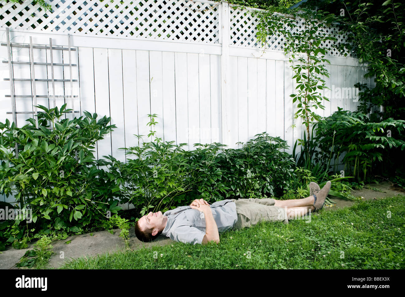L'uomo la posa su un marciapiede in un cortile di fronte un white Picket Fence, Montreal, Quebec Foto Stock