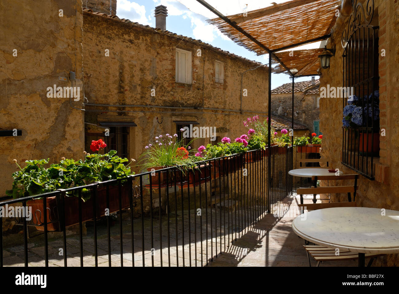 Toscana (Toscana) Italia - vasi di fiori appesi a un metallo ringhiere con vedute della città medievale di Casale Marittimo. Foto Stock