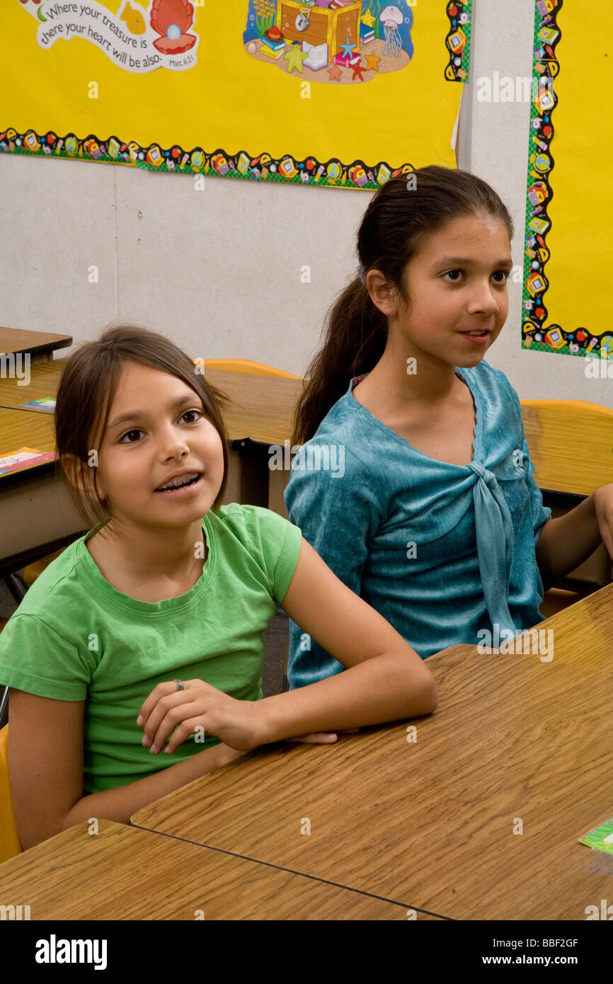 Due giovani ispanici multi etnico ragazze 8-9 anno Olds Stati Uniti seduta a parlare e ascoltare in aula signor © Myrleen Pearson Foto Stock