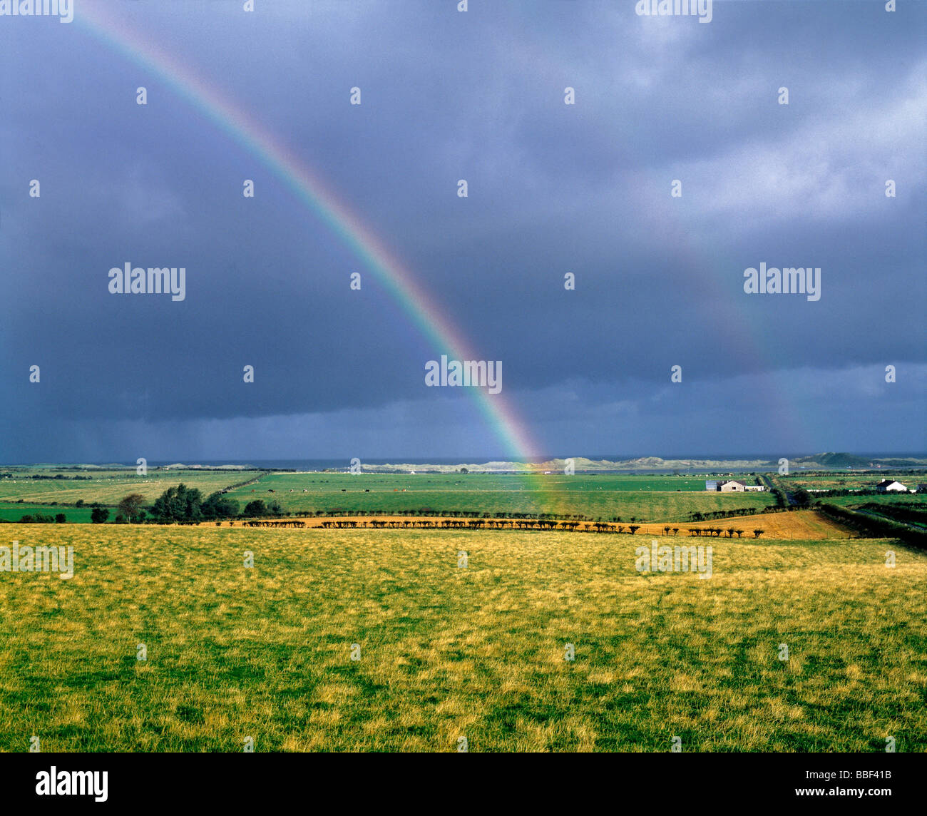 A tarda sera sun crea un arcobaleno in un cielo nuvoloso vicino alla costa di Antrim in Irlanda del Nord Foto Stock