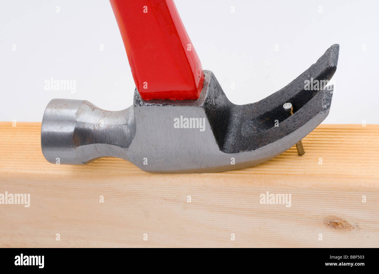 Utilizzando un martello da carpentiere per rimuovere un chiodo a partire dal legno Foto Stock
