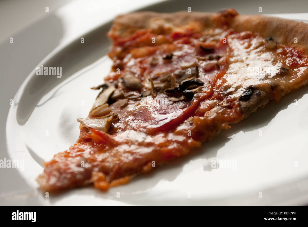 Fetta di pizza con funghi e cipolle su un piatto bianco. Foto Stock