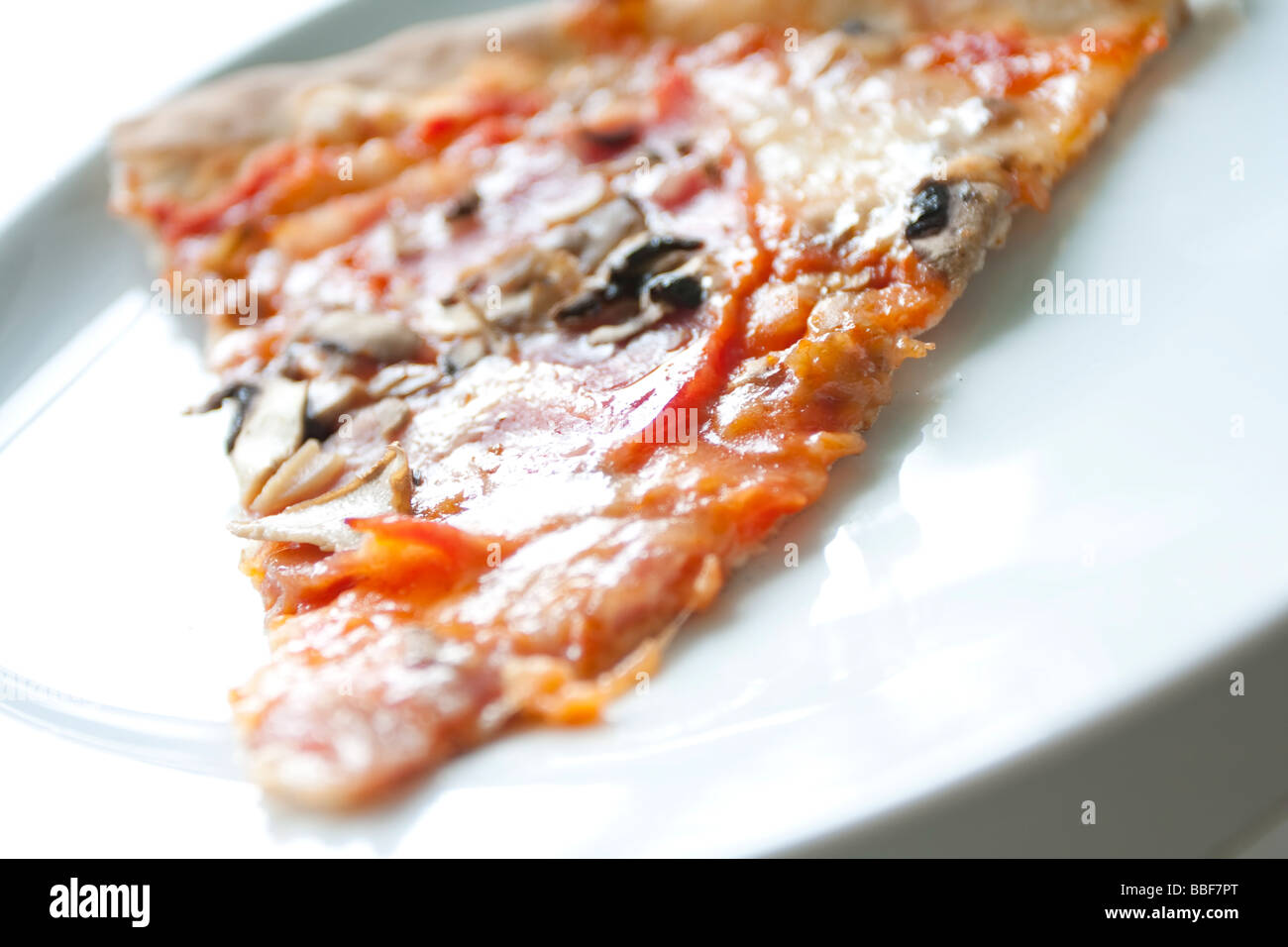 Fetta di pizza con funghi e cipolle su un piatto bianco. Foto Stock