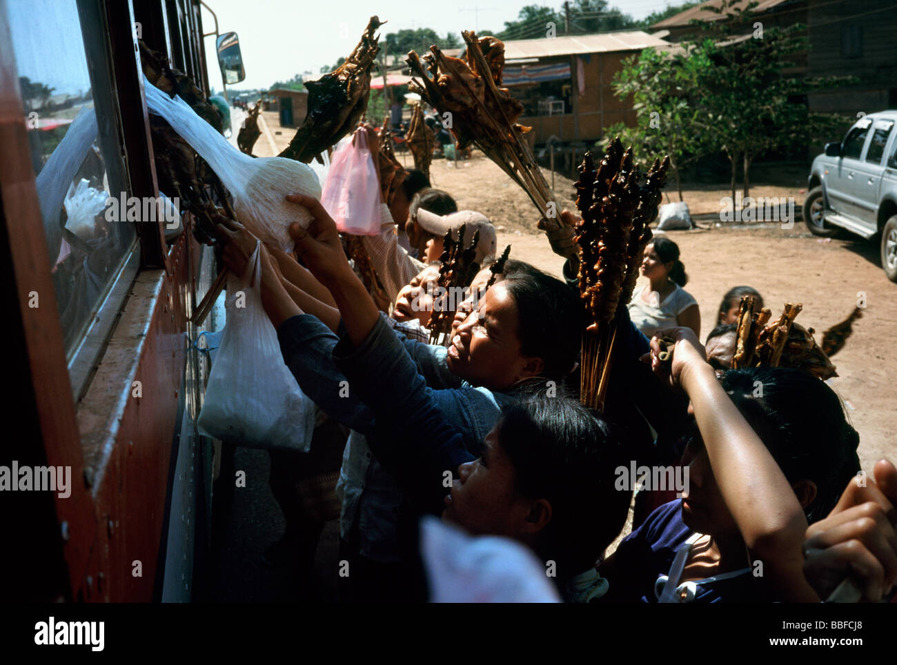 Strada locale i fornitori che offrono spuntini ai passeggeri di un autobus in viaggio da Savannakhet a Paxxe in Laos. Foto Stock